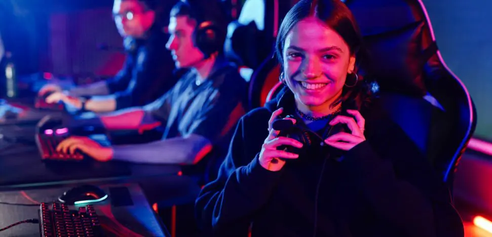Girl at computer, holding a pair of headphones.