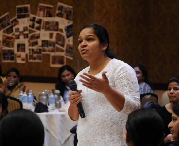 Indian mother standing with a microphone at at a parent teacher meeting